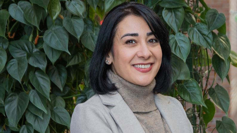 Dr. Mahsa Samsami steht vor einer Blätterwand