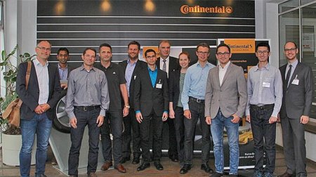 Gruppe steht vor einer Plakatwand mit dem Schriftzug "Continental".