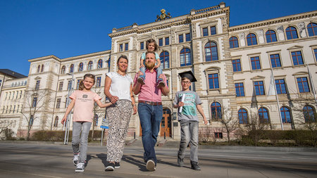 Eine Familie vor dem Hauptgebäude der TU Chemnitz.