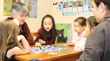Frau spielt mit Kindern an einem Tisch