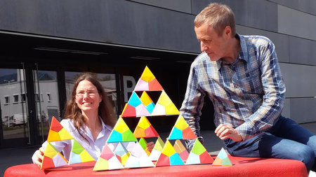 Zwei Personen stapeln Tetraeder auf.