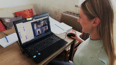 Frau sitzt im Wohnzimmer vor einem Computermonitor.