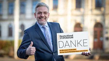 Mann im Anzug hält ein Schild in der Hand