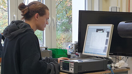 Ein junger Mann blickt auf den Monitor einer technischen Anlage.
